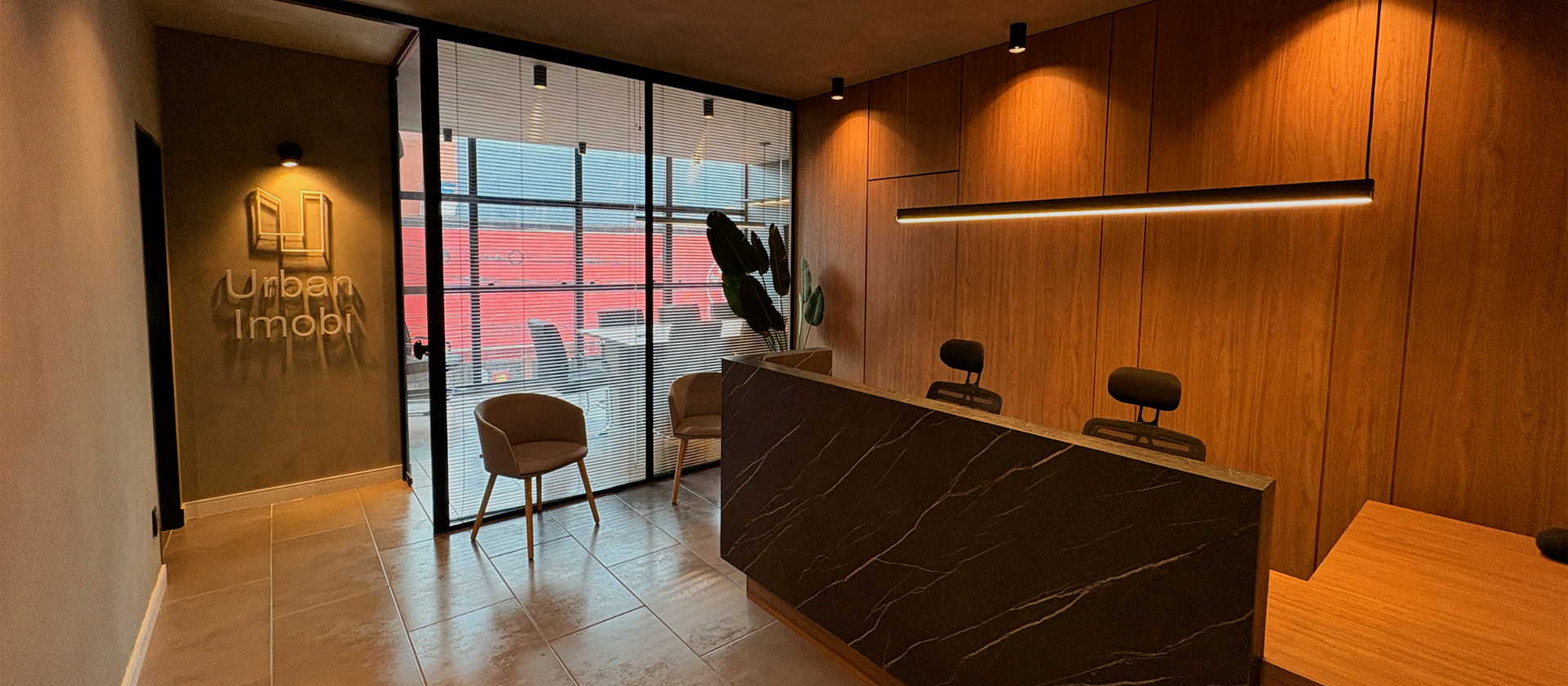 Recepção do escritório da Urban Imobi, com balcão em mármore e painel de madeira